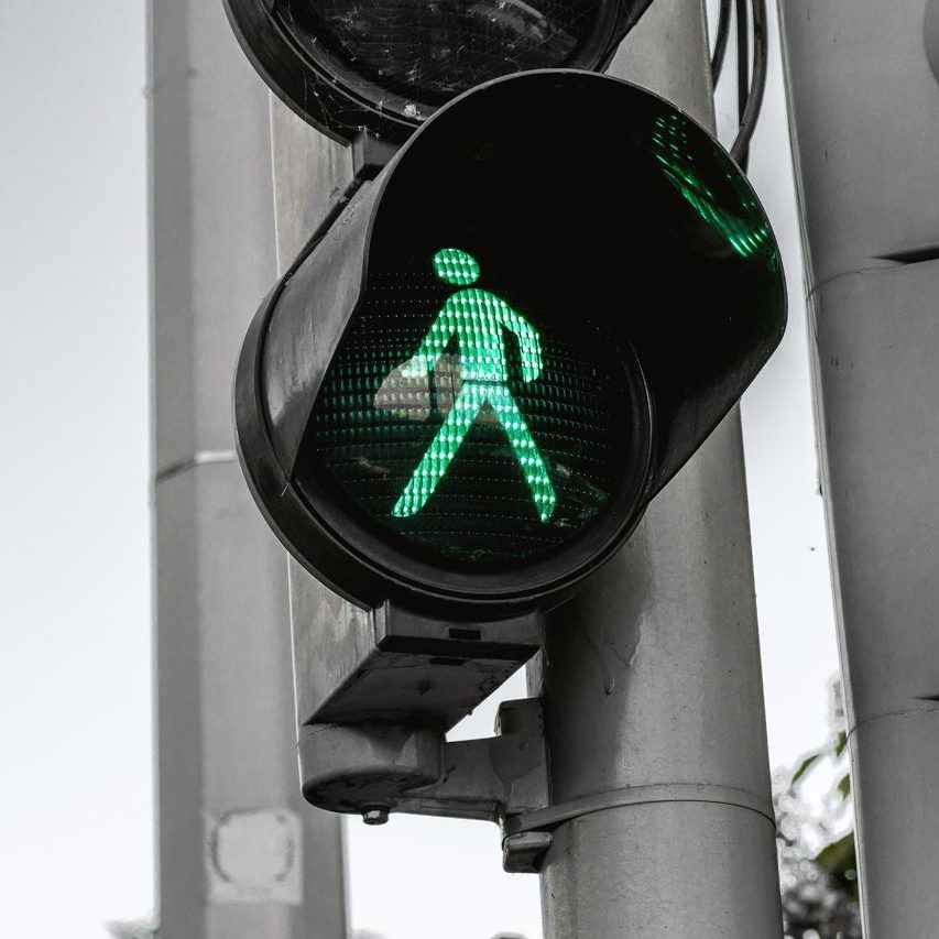 testimonial-07-free-img Close-up of a green pedestrian traffic signal indicating walk at an intersection.