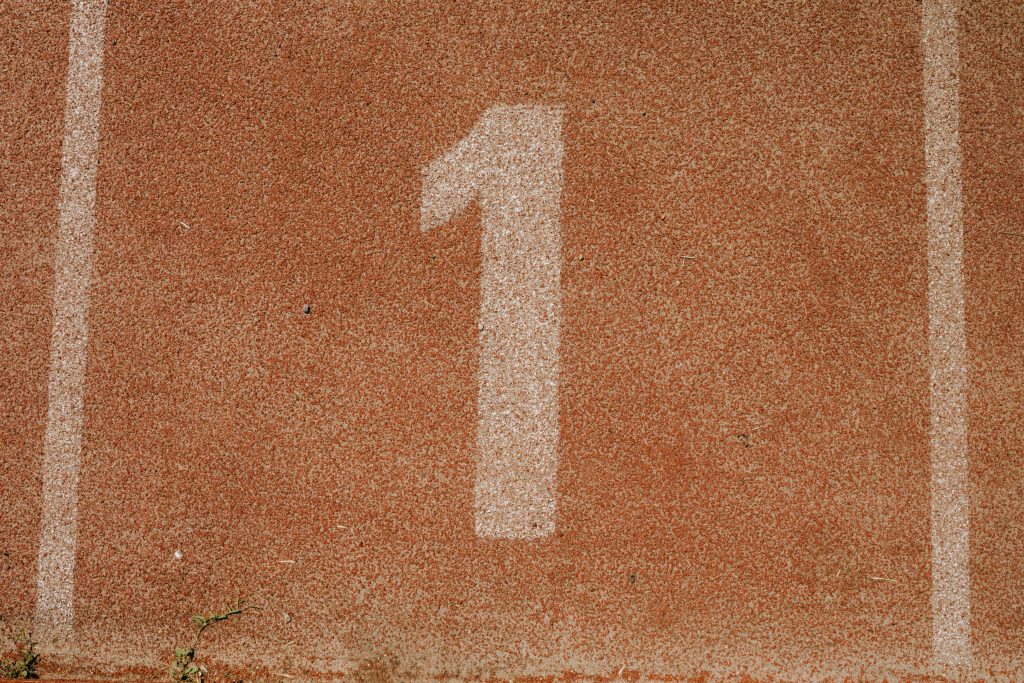 Close-up image of number one lane on a running track, symbolizing first place.